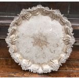 A silver footed salver having raised foliate pattern around the rim,