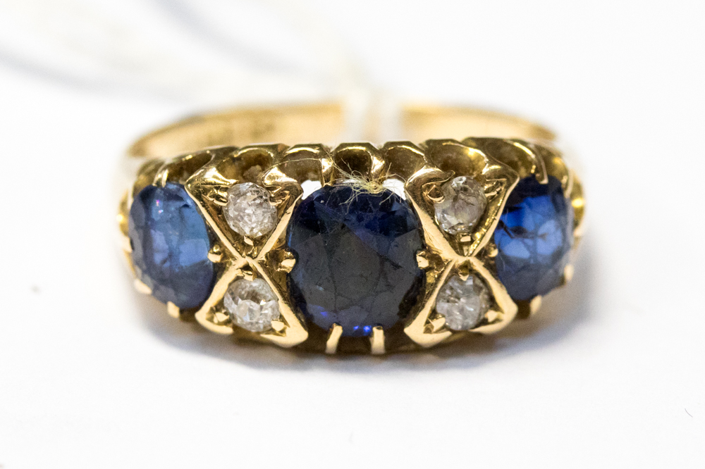 A sapphire and diamond ring, the three graduated oval sapphires interspersed with four diamonds,