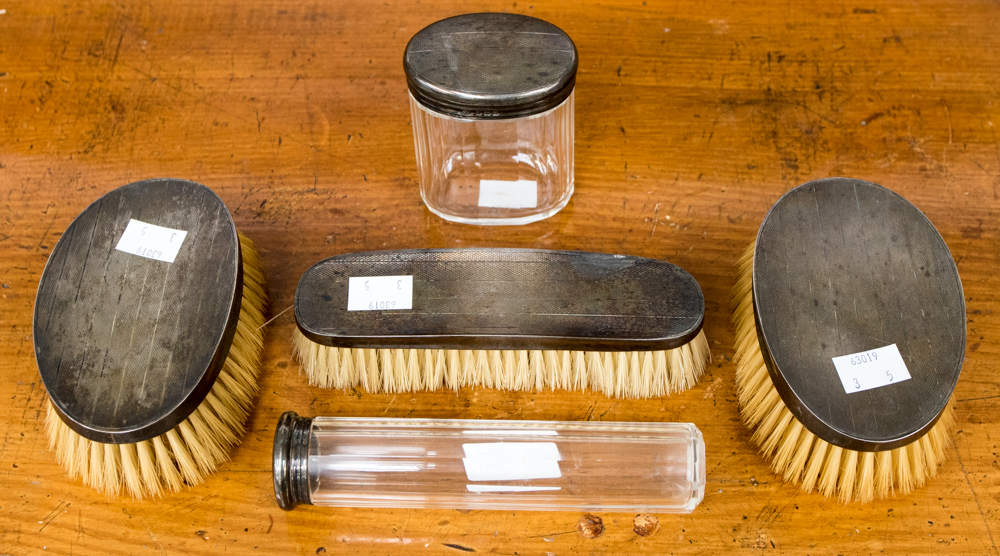 A George V silver toilet set including glass jars and silver backed brushes, Adie Bros,