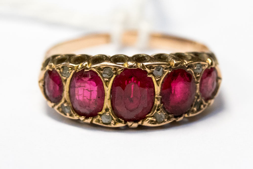 A rose metal and red stone ring, comprising five graduated oval stones, size U,
