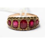 A rose metal and red stone ring, comprising five graduated oval stones, size U,