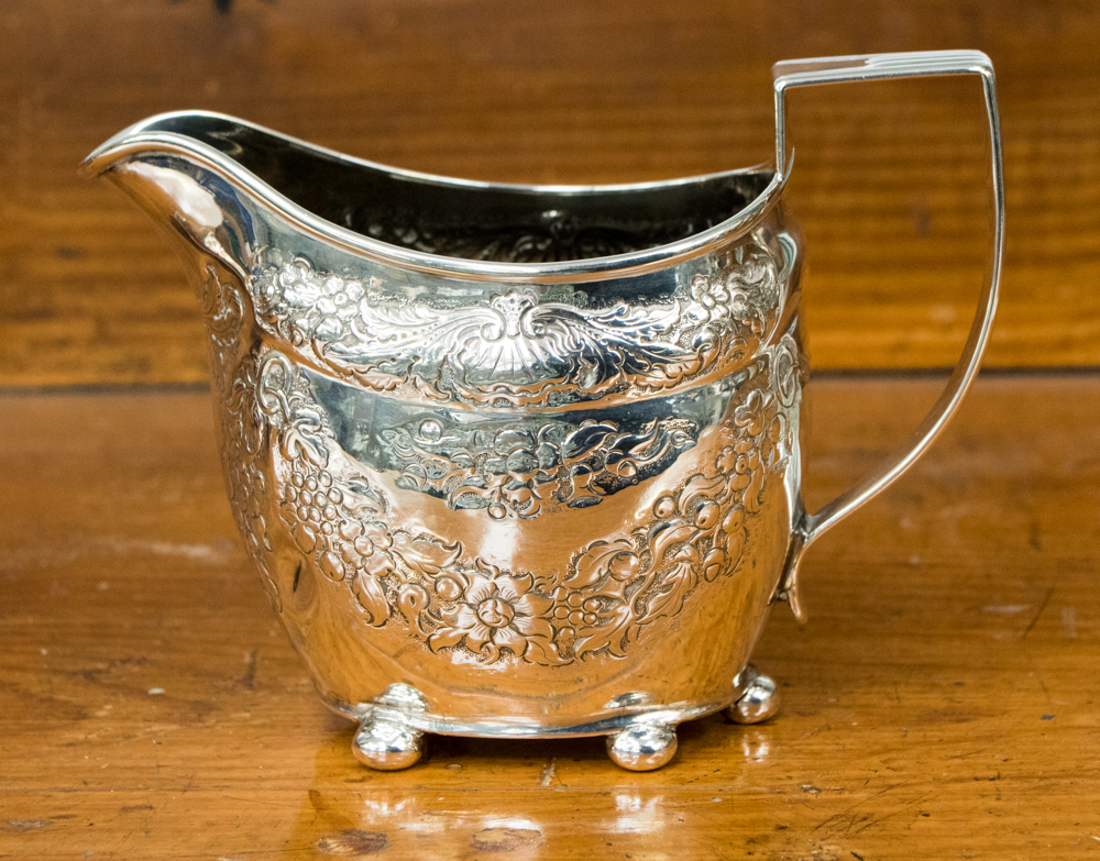 A Georgian silver cream jug with later embossed decoration of floral swags,