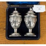 A boxed pair of pepperettes decorated with swags and column style repouse decoration,