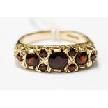 A garnet and 9ct gold ring, set with nine mix cut round garnets in a scroll mount, ring size O½,