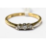 A three stone diamond ring, the diamonds claw set in platinum, on an 18ct gold band, size Q 1/4,