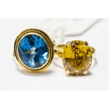 A 14ct gold ring set with a large oval blue topaz, with a rub over setting and rope detail,