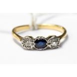 A yellow metal (probably 18ct) ring set with a central oval sapphire with single diamonds set