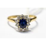 A sapphire and diamond oval cluster 18ct gold ring, centre oval blue sapphire approx 5.7mm x 4.