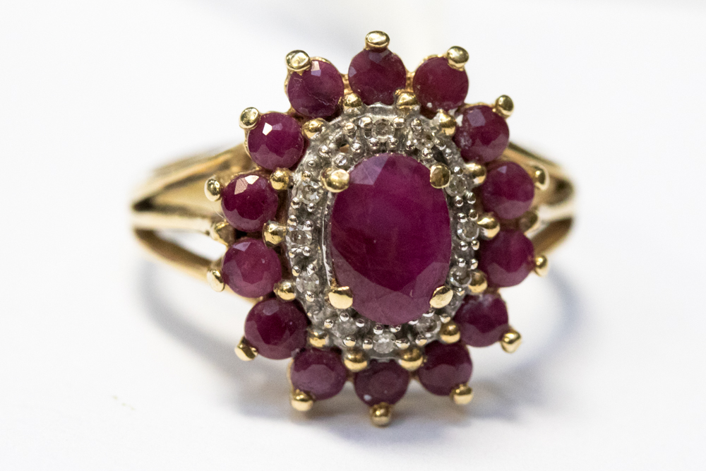 A ruby cluster ring set in yellow metal,