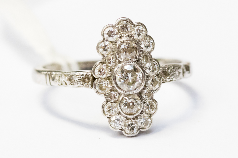 A 18ct white gold diamond cluster ring, the three dominant old-cut diamonds set vertically,