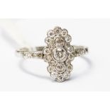 A 18ct white gold diamond cluster ring, the three dominant old-cut diamonds set vertically,