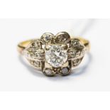 An unusual diamond cluster ring, claw set with a central brilliant cut diamond,