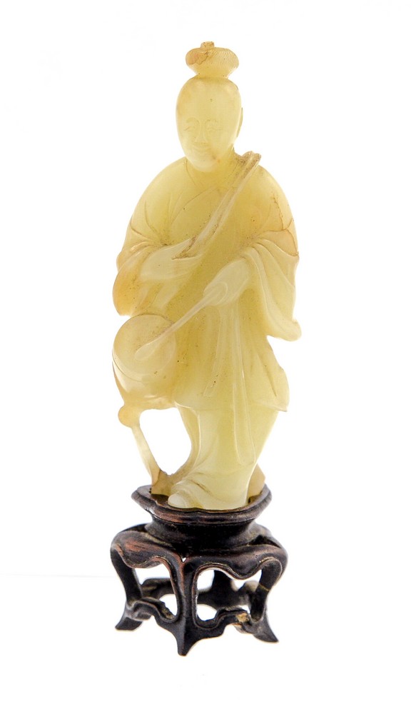 A Chinese pale jade figure, 18th/19th Century, carved as a standing robed figure beating a drum,