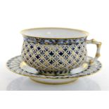 A Sevres reticulated tea cup and saucer, circa 1884, the cup in underglaze blue with bamboo handle,