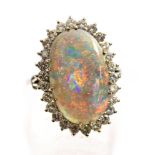 An 18ct white gold opal and diamond dress ring, claw set cabochon black opal,