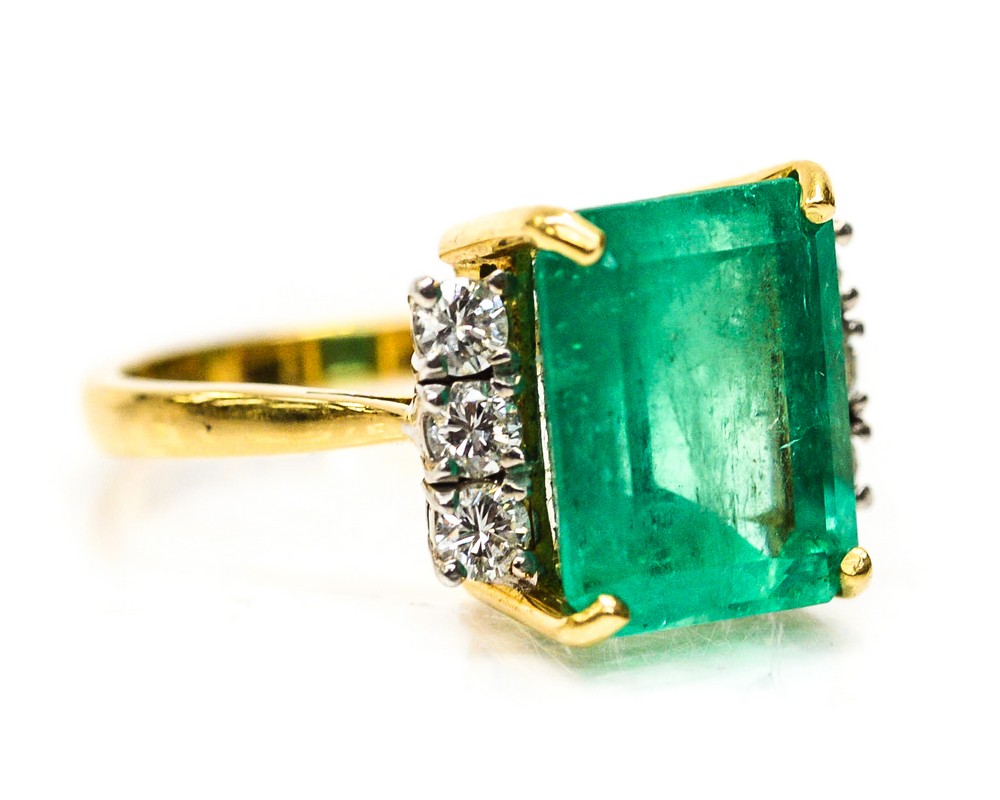 An emerald and diamond 18ct yellow gold ring the centre claw set emerald cut emerald measuring 12mm