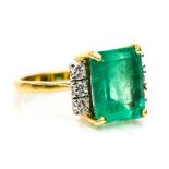 An emerald and diamond 18ct yellow gold ring the centre claw set emerald cut emerald measuring 12mm