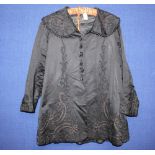 An early Edwardian black sateen long line jacket, embellished with embossed flower and vine design,