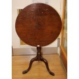 A George III oak tilt top tripod table, the plank top raised on a bird-cage mechanism,