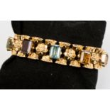 An 18ct stamped gold bracelet set with amethyst, citrine, blue topaz, garnet,