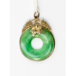 A jadeite donut ring style pendant with yellow metal surround in the form of leaves,