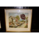 A needlework framed study of a cottage,