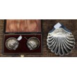 A pair of Edwardian silver salts and spoons, shell shaped bowls on three ball feet, Henry Morton,