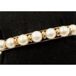 One 14ct gold hinged bangle with eight cultured fresh water pearls set to the top,