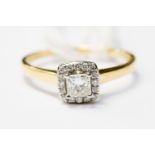 A princess cut diamond ring, with a halo surround of small diamonds,