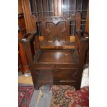 An early 20th Century oak hall seat, the plank seat opening to reveal a storage section,