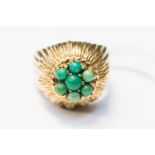 A 1950s 9ct gold and turquoise dress ring with a gold flower layer detail set to the top with seven