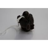 A Japanese dark wood carved Netsuke depicting a Bird with a twig with berries in it's beak,