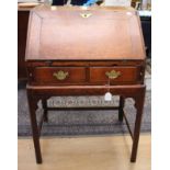 A George III oak bureau on stand, the fall front opening to reveal a fitted interior,