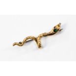 A Victorian serpent brooch in gilt metal, with a green stone set to the head and red eyes,
