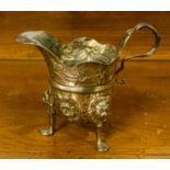 A George III or later white metal cream jug, raised on three hoof feet, later chased, 179 grams/5.