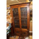 An early 20th Century oak bookcase, the upper section with two glazed doors with leaded glass,