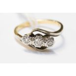 A three stone diamond ring, with cross over detail in 18ct yelow and white gold, finger size K½,