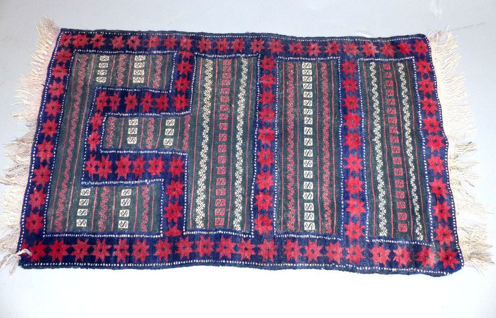 An Afghan Belouch tribal rug, part flat weave, part pile, in traditional deep reds and indigo blue,