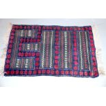 An Afghan Belouch tribal rug, part flat weave, part pile, in traditional deep reds and indigo blue,