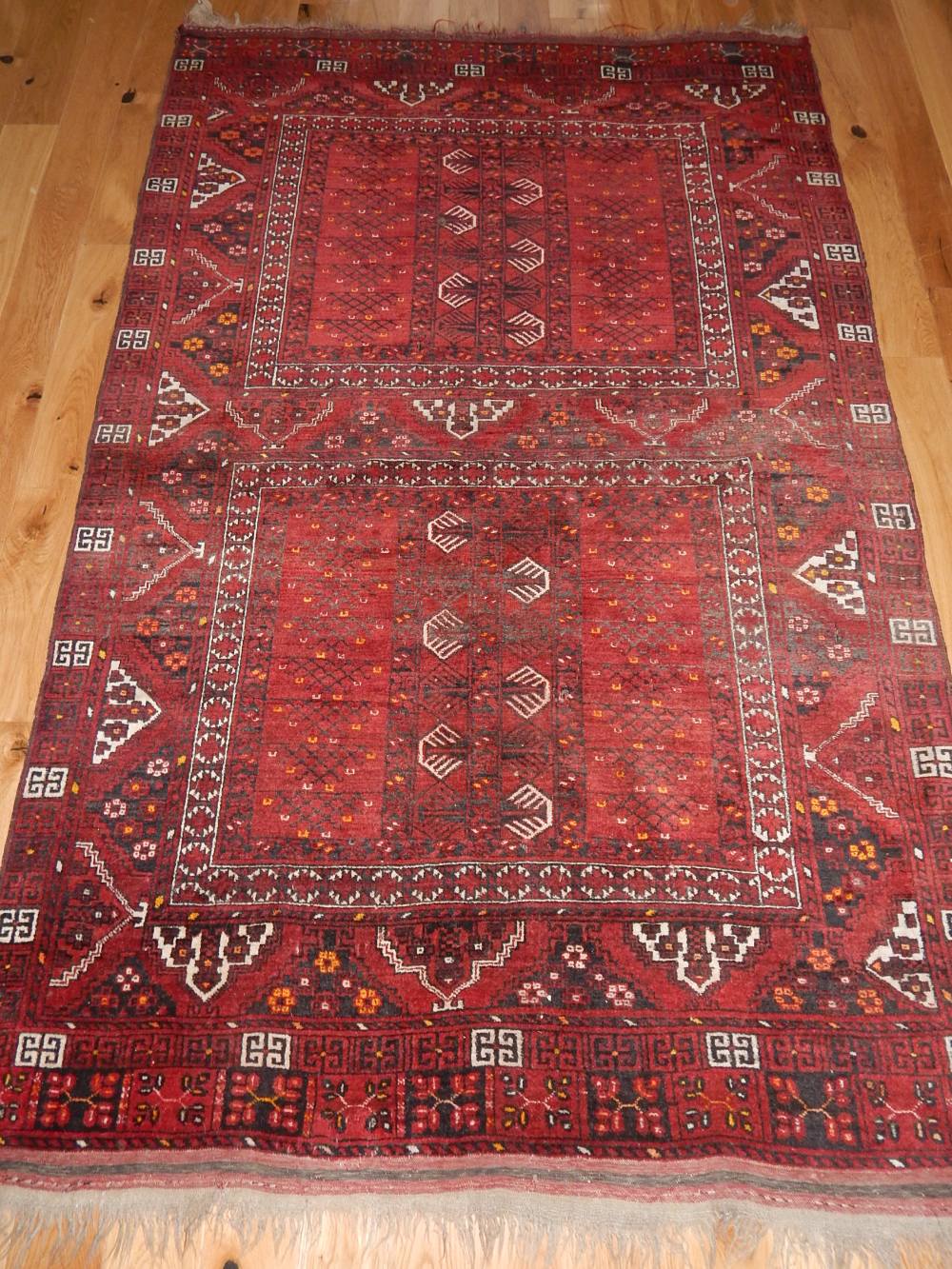 Persian Turkoman red ground carpet with two geometric panels within a wide border, 250 x 158cm.