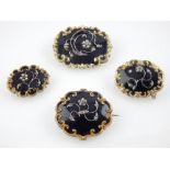 Four memoriam scroll frame brooches, black enamel with seed pearl floral decoration. (4)