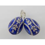 Pair of blue enamel egg pendants, trailing floral decoration. (2)