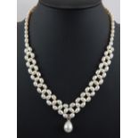 Natural pearl graduated necklace with woven links, central drop and white metal clasp.