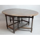 An oak circular dropleaf gateleg action kitchen dining table on bobbin supports joined by stretcher,