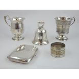 Four silver hallmarked items comprising cigarette case, Chester 1912, hand bell Birmingham 1928,