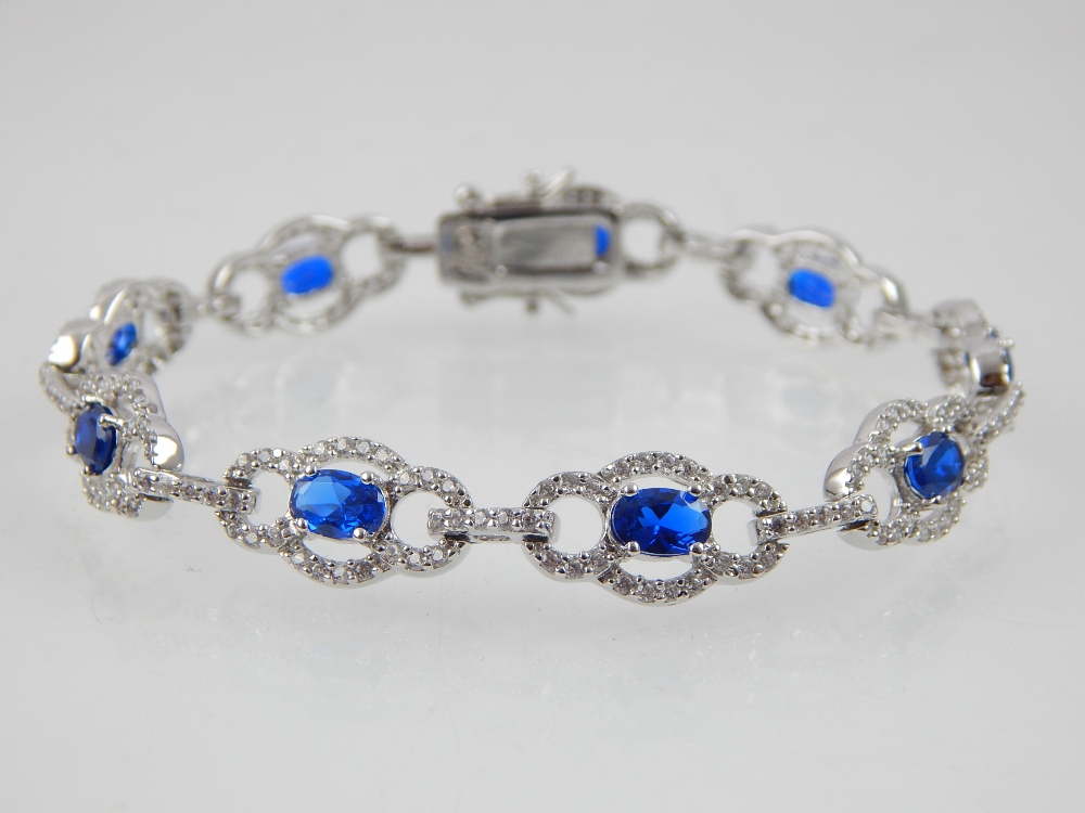 Silver cubic zirconia and blue stone bracelet with open oval links.