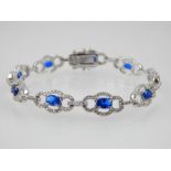 Silver cubic zirconia and blue stone bracelet with open oval links.