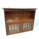 Arts & Crafts style oak wall cabinet of serpentine form with shelf above a pair of astragal doors,