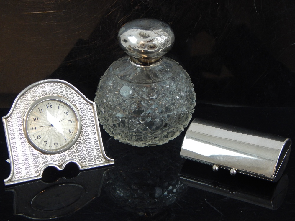 George V turned silver bedside timepiece frame, a silver mounted scent bottle and a plated compact.