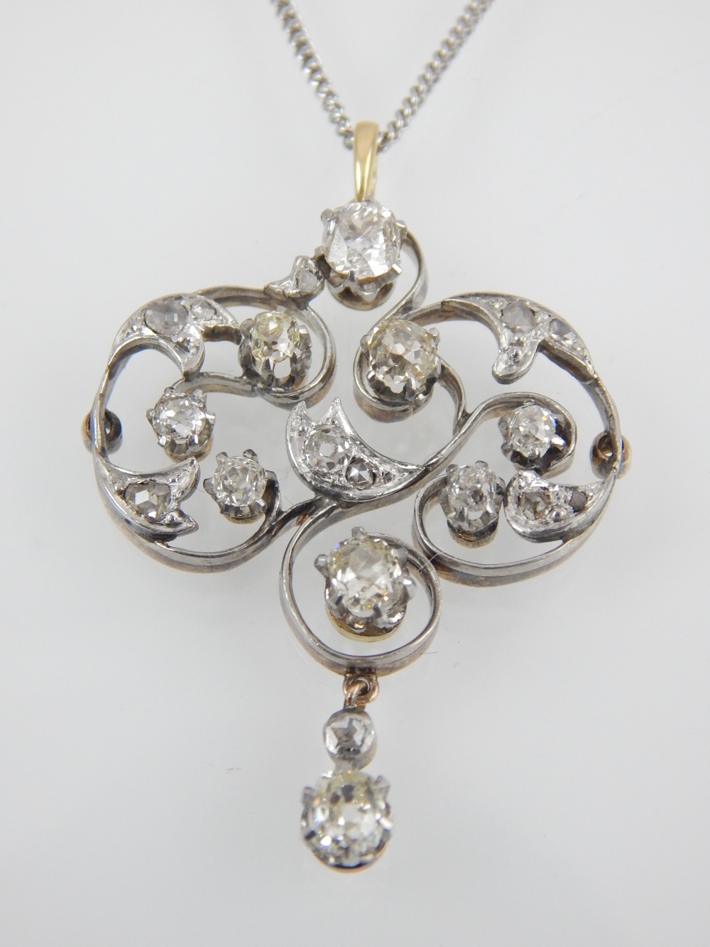 An antique Art Nouveau diamond pendant in yellow gold on a silver chain,